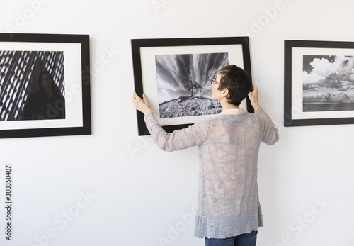 Woman hanging photographs in art gallery