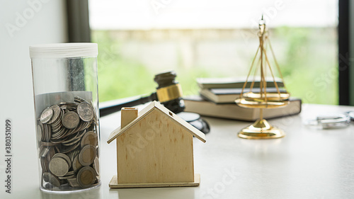 Money jar, coin and house model on the tableJustice Scales and books and wooden gavel on table. Justice concept