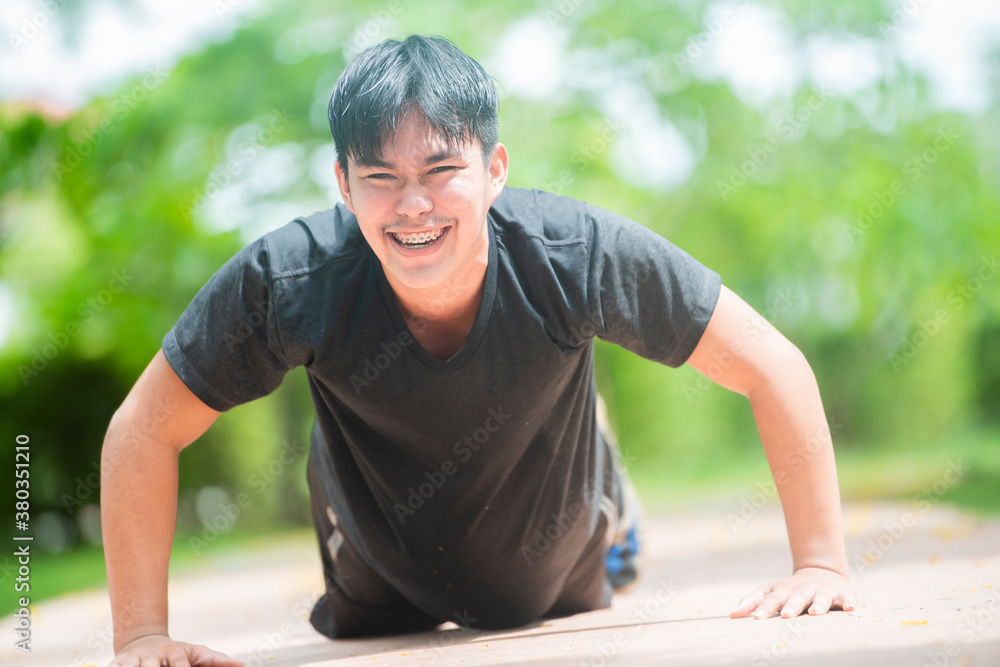 Fototapeta premium Happy asian man athlete exercising push up outside in sunny sunshine. Copy space