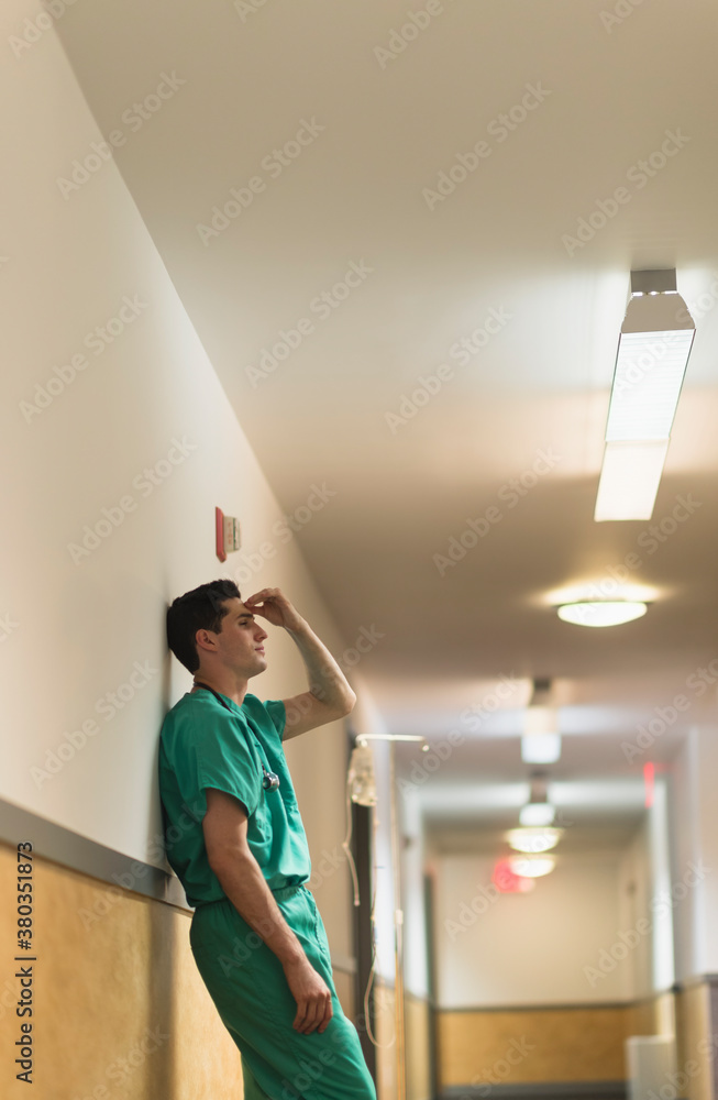 Tired doctor standing in hallway Tired doctor standing in hallway