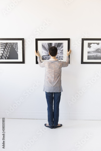 Woman hanging photographs in art gallery