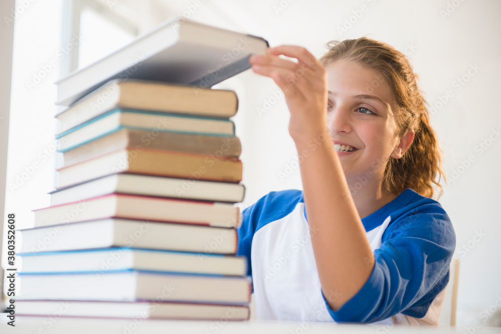 Portrait of teenage girl (12-13) stacking books Portrait of teenage girl (12-13) stacking books