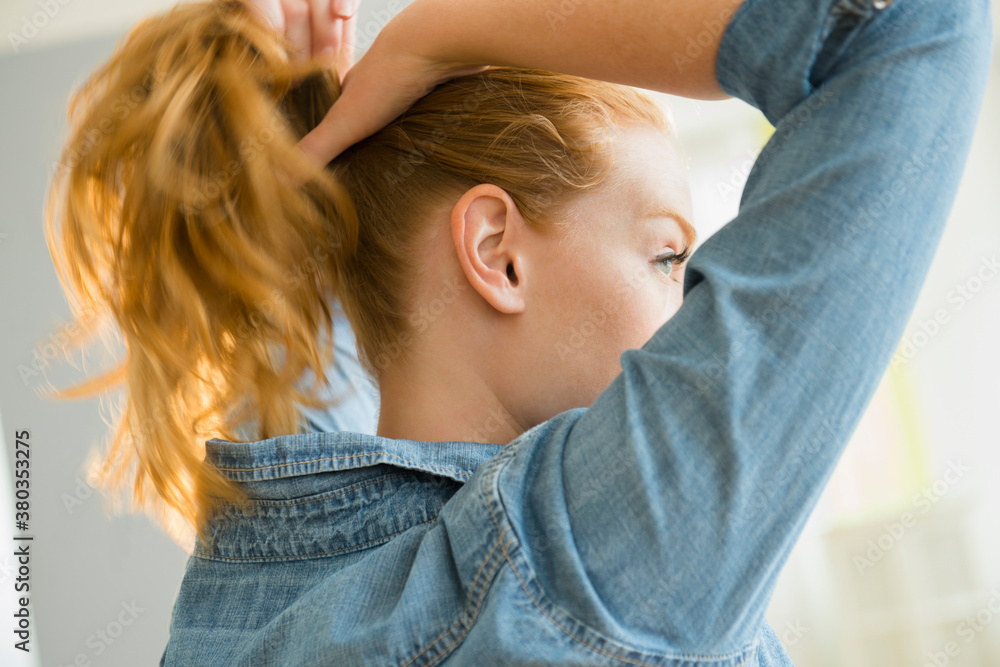 Young woman tying hair Young woman tying hair