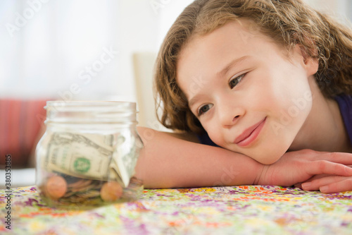 Girl (10-11) girl looking at jar full of money photo