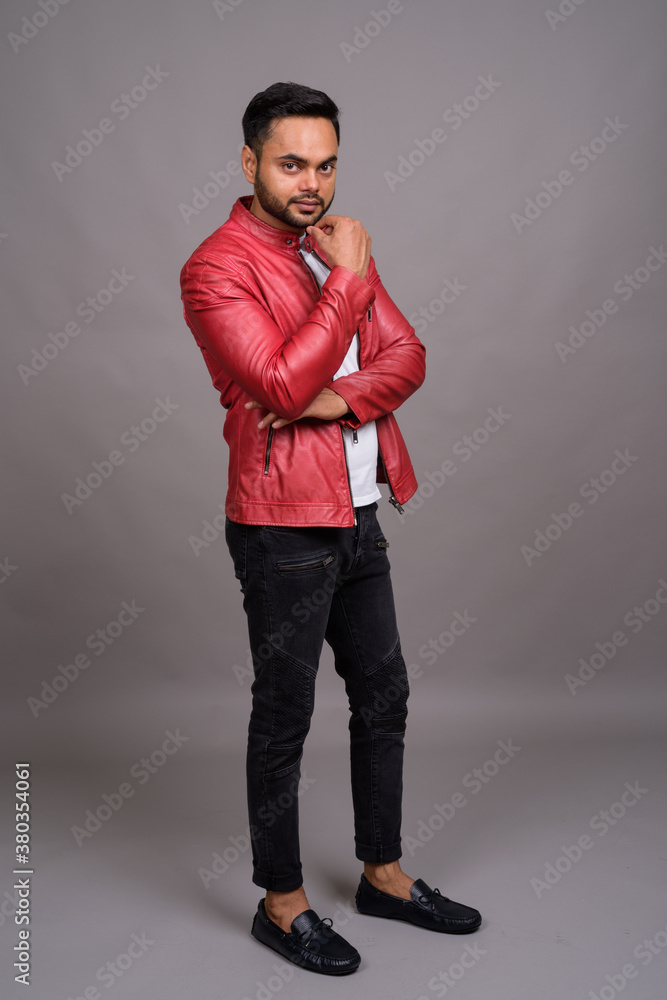 Young bearded Indian man against gray background