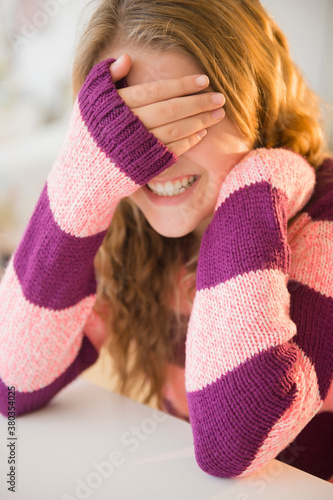 Girl (12-13) grinning and covering eyes photo