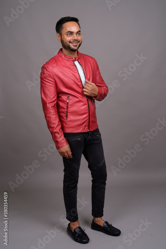 Young bearded Indian man against gray background