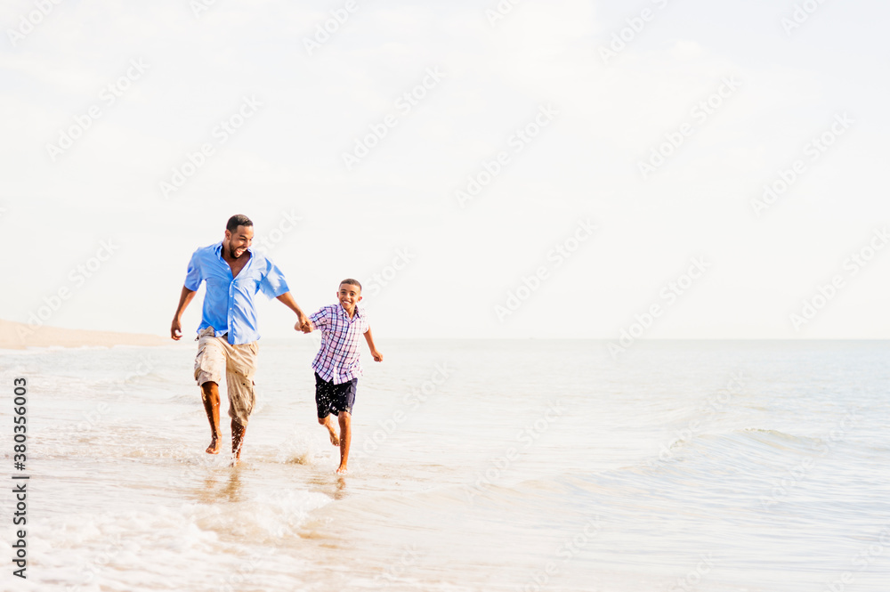 Father and son (10-11) running on beach Father and son (10-11) running on beach