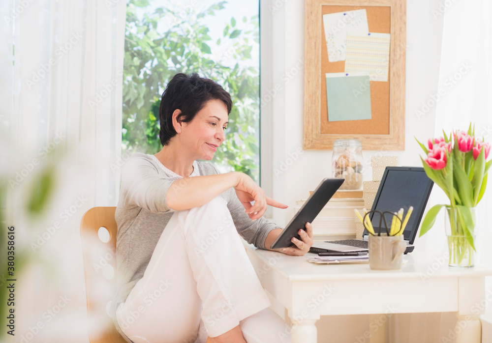 Mature woman using digital tablet and laptop Mature woman using digital tablet and laptop
