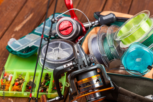 Different fishing tacles with lures and reels on wooden brown background with place for text.