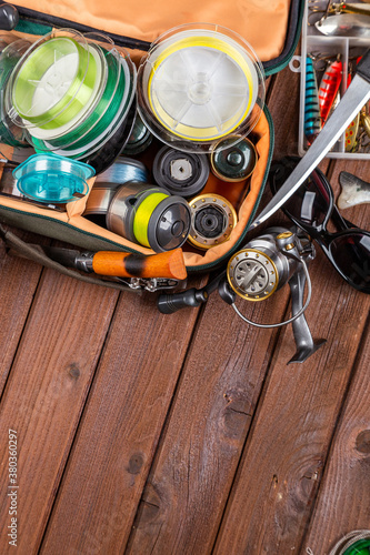 Different fishing tacles with lures and reels on wooden brown background with place for text.