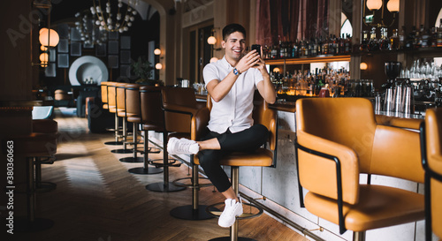 Happy man taking shot with smartphone while sitting at counter