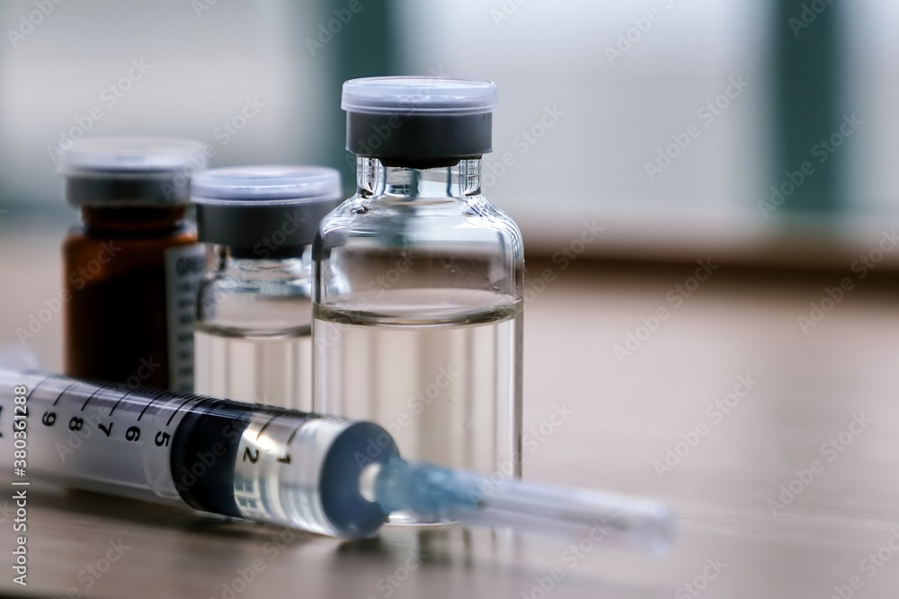 Vaccine vials and syringe on table. Vaccine vials and syringe on table.