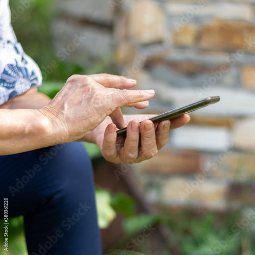 Crop view of elderly woman hands holding a smartphone