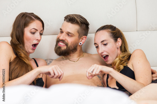 couple having threesome fun in bed with another woman photo