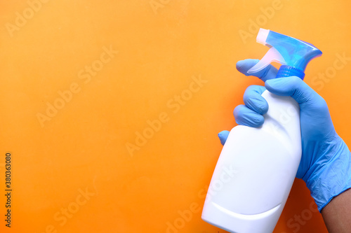 Fotografie Person hand in disposable gloves holding disinfectant spray