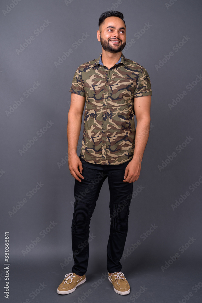 Young bearded Indian man against gray background Young bearded Indian man against gray background