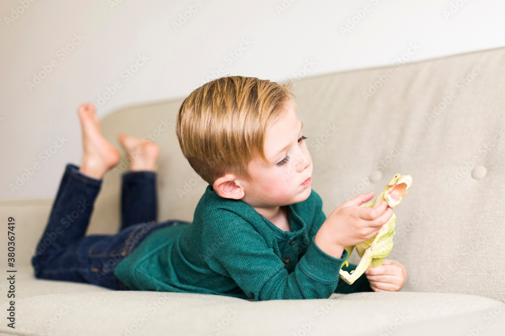 Boy (2-3) playing with toy dinosaur on sofa Boy (2-3) playing with toy dinosaur on sofa