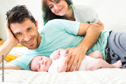 Happy parents with baby boy (6-11 months) lying on bed photo