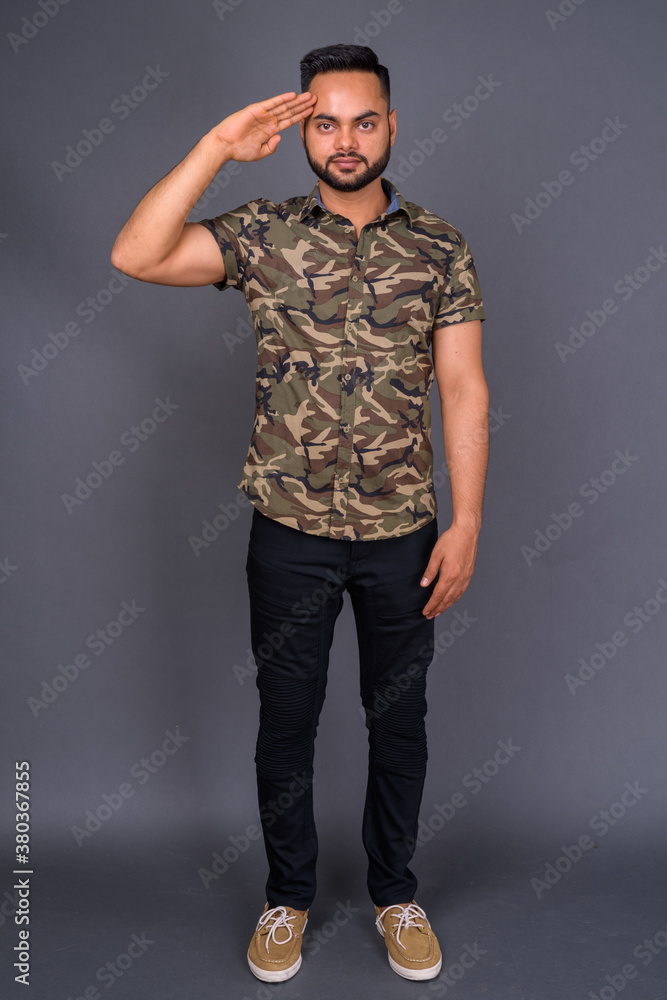 Young bearded Indian man against gray background Young bearded Indian man against gray background