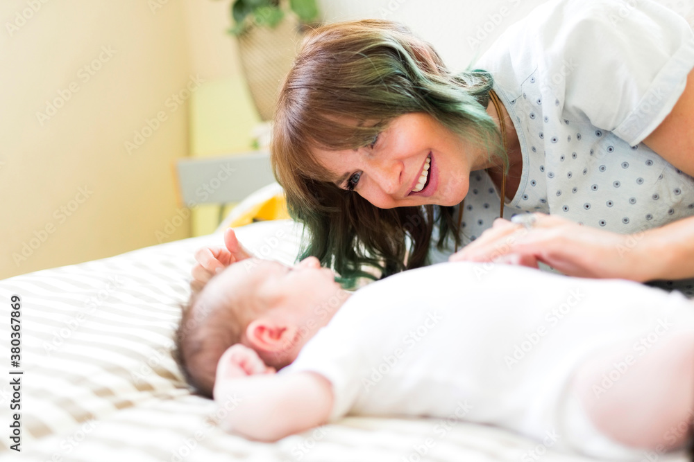 Smiling mother lying on bad with baby boy (6-11 months) Smiling mother lying on bad with baby boy (6-11 months)