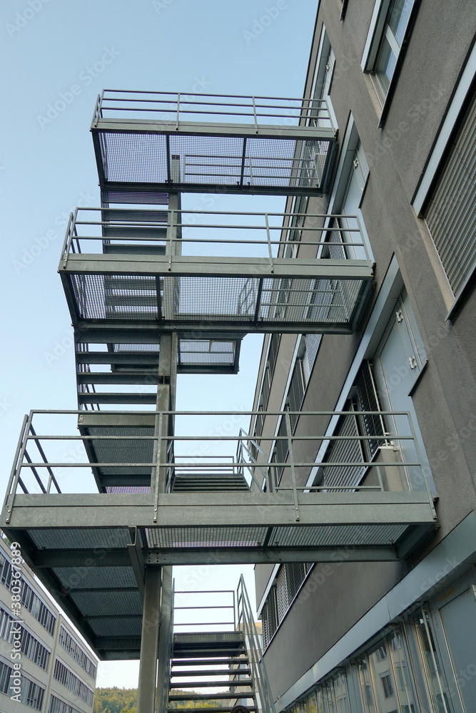 Obraz premium Long set of metal stairs, fire escape route, attached to outside of modern industrial and administrative brick building in Dietikon, Switzerland.