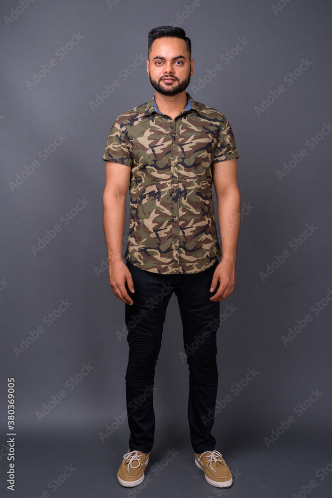 Young bearded Indian man against gray background Young bearded Indian man against gray background