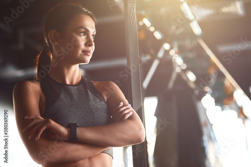 Fitness girl. Young attractive fit woman wearing sportswear keeping arms crossed and looking away while standing at gym