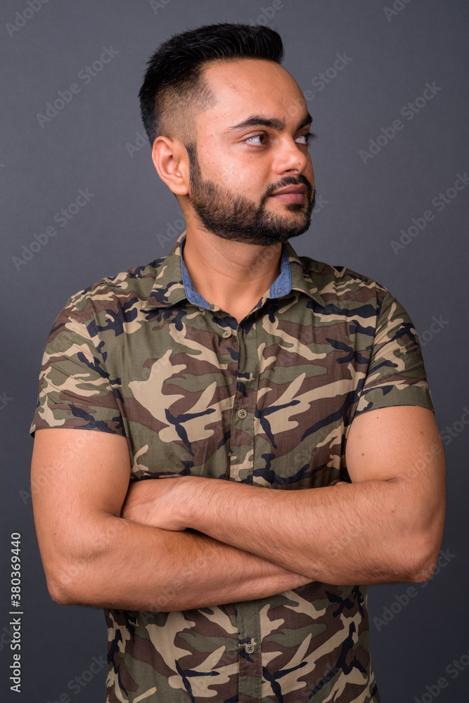 Young bearded Indian man against gray background Young bearded Indian man against gray background