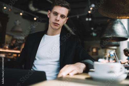 Thoughtful guy with cup of coffee in cafe