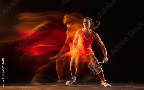 High jump. Professional female tennis player training isolated on black studio background in mixed light. Woman in sportsuit practicing. Healthy lifestyle, sport, workout, motion and action concept.