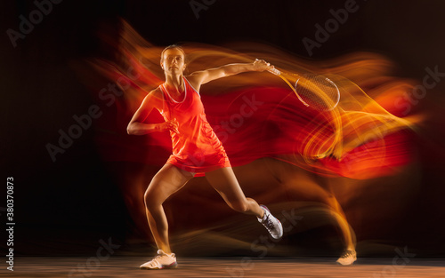 Competition. Professional female tennis player training isolated on black studio background in mixed light. Woman in sportsuit practicing. Healthy lifestyle, sport, workout, motion and action concept.