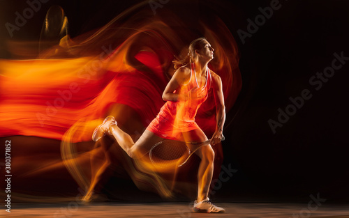 Competition. Professional female tennis player training isolated on black studio background in mixed light. Woman in sportsuit practicing. Healthy lifestyle, sport, workout, motion and action concept. © master1305