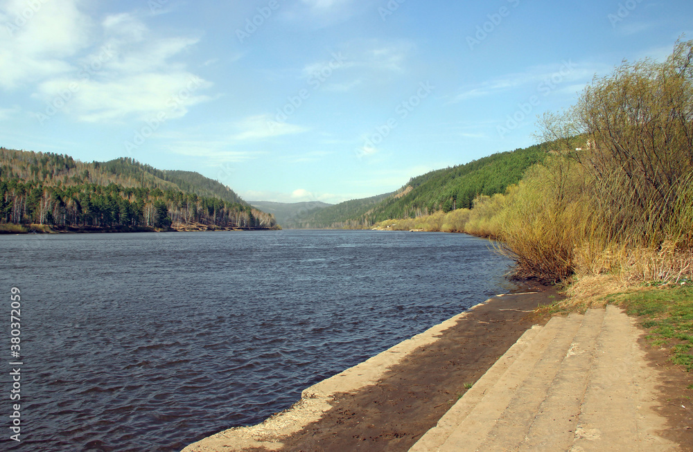 Wide concrete steps lead to the river. There is an amazing view of the water ripples and wooded hills in the distance. Wide concrete steps lead to the river. There is an amazing view of the water ripples and wooded hills in the distance.