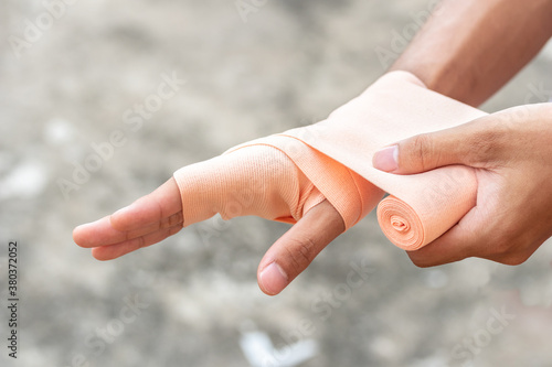 Close-up of a man hand wrapping elastic bandage. Wounded hand cover with bandage. © lllonajalll