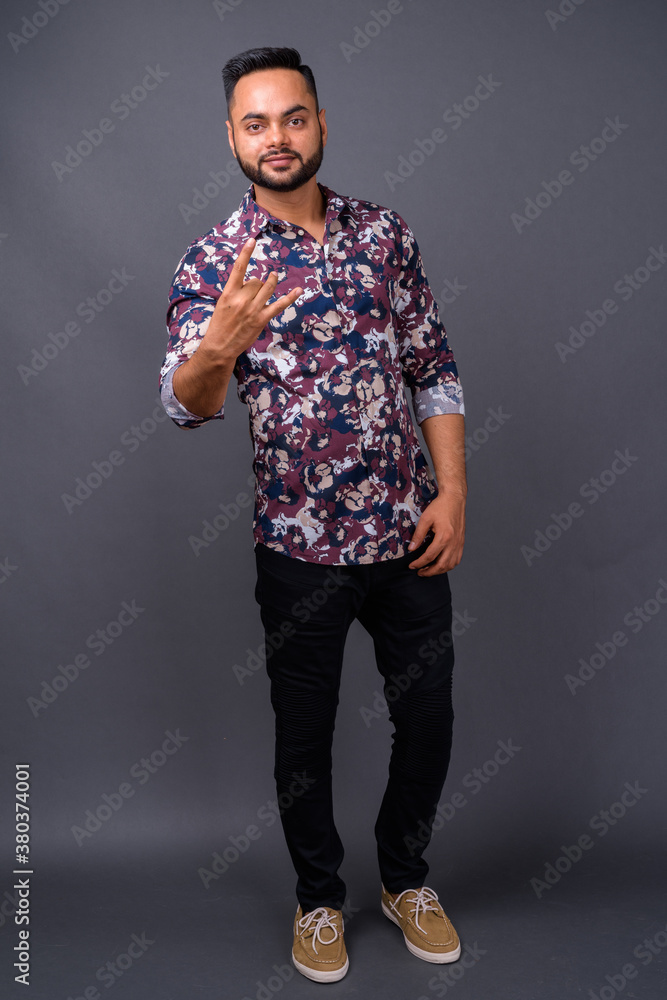 Obraz premium Young bearded Indian man against gray background