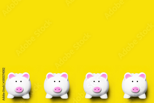 Money diversification background. Four piggy bank isolated on yellow. Home budget planning empty copy space. Coins and banknotes collecting. Cash saving backdrop.