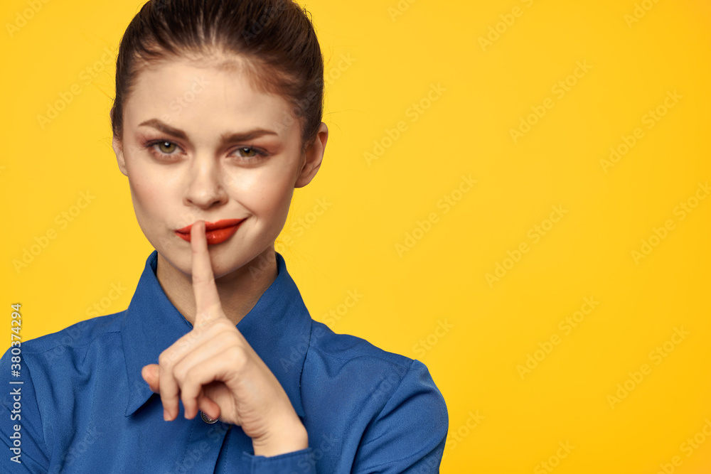 Portrait of a woman in a blue shirt with bright makeup red lips yellow background cropped view Portrait of a woman in a blue shirt with bright makeup red lips yellow background cropped view