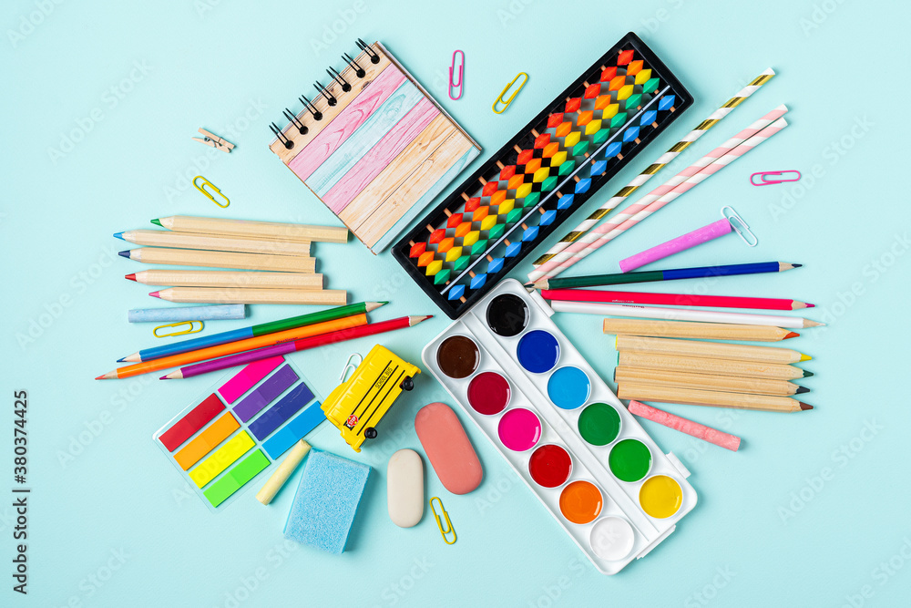 Fototapeta premium Top view of modern bright blue office desktop with school supplies on table. Back to school concept
