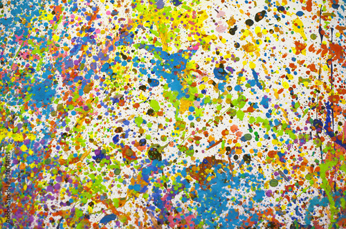Multicoloured paint splatters on a white wall