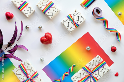 Christmas gifts with rainbow ribbon in LGBTQ community flag colors. Flat lay with Xmas decor.