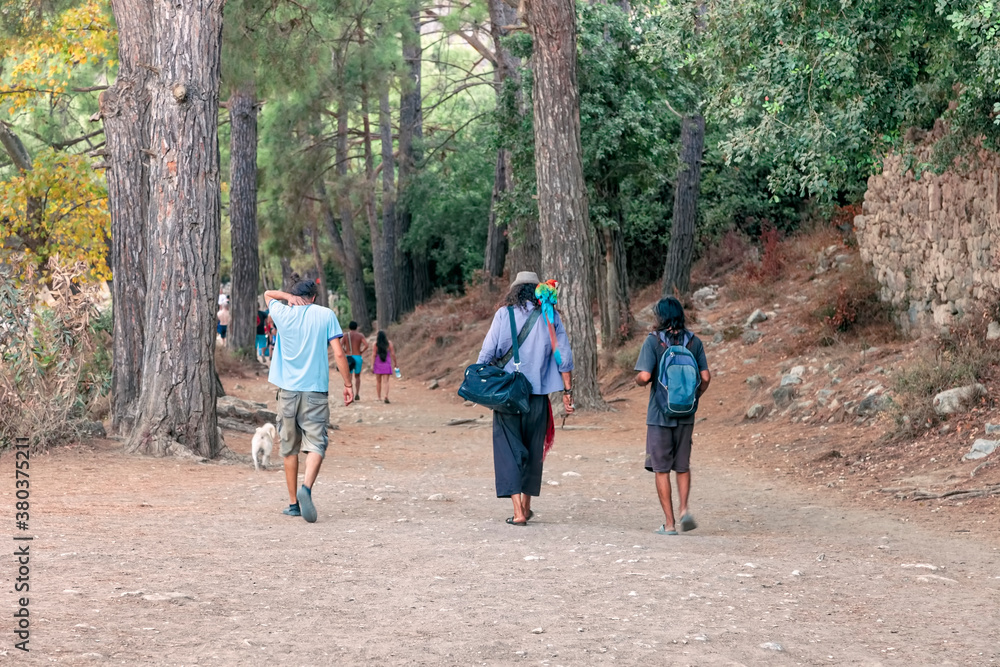 Rear view of people walking on a footpath between pine trees in Olympos, Turkey Rear view of people walking on a footpath between pine trees in Olympos, Turkey
