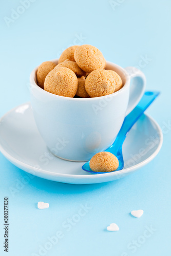 group of amaretti in a blue cup with spoon on blue background photo