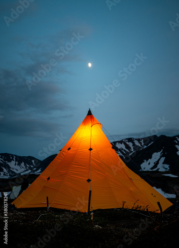 a tent of geologists glowing in the night in the mountains of the Kamchatka peninsula on the Bolshoi Semyachik volcano