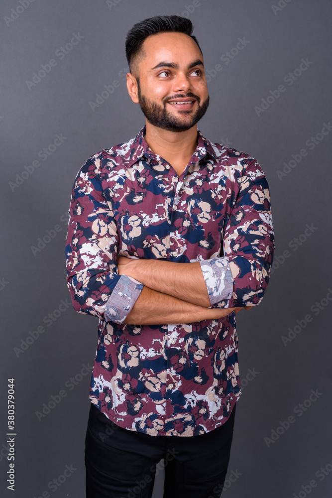 Young bearded Indian man against gray background Young bearded Indian man against gray background