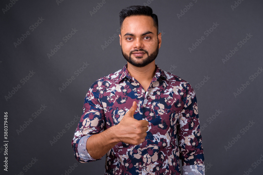 Young bearded Indian man against gray background Young bearded Indian man against gray background