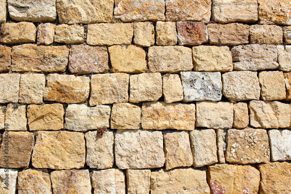 horizontal background of rows of old wall blocks in summer in the sun with relief and texture horizontal background of rows of old wall blocks in summer in the sun with relief and texture