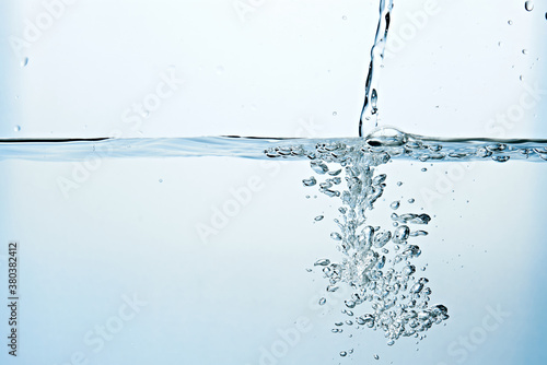 Close up of clean blue water and splash with bubbles of air isolated on white background. Diet, health and nature concept. Copy space..