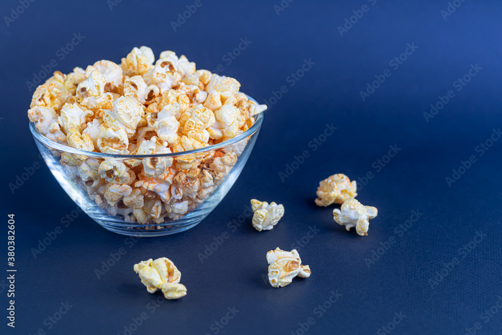A clear bowl of popcorn on the darkened surface. A clear bowl of popcorn on the darkened surface.