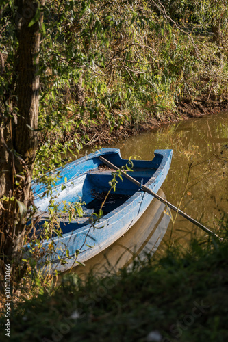 Vertical shot of an old wooden boat on a river in the woods - nostalgic scene photo